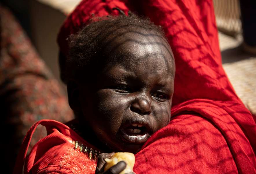 Sudan: Et trist barn på skulderen til sin mor. Foto: Kirkens Nødhjelp/Håvard Bjelland. 