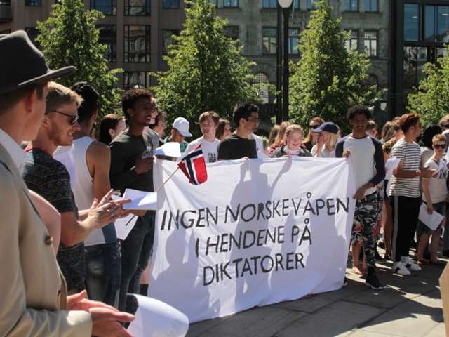 mennesker som holder et stort budskap med følgende tekst: ingen norske våpen i hendene på diktatorer