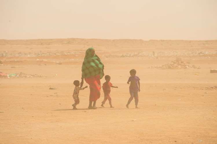 Mor med tre barn i ett tørt område