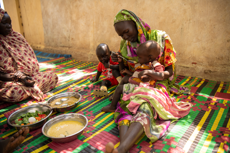 En mor mater barna sine på Kirkens Nødhjelps helseklinikk i Bilel i Darfur i Sudan. Hver dag sliter 9.6 millioner mennesker i Sudan med å skaffe nok mat på bordet.