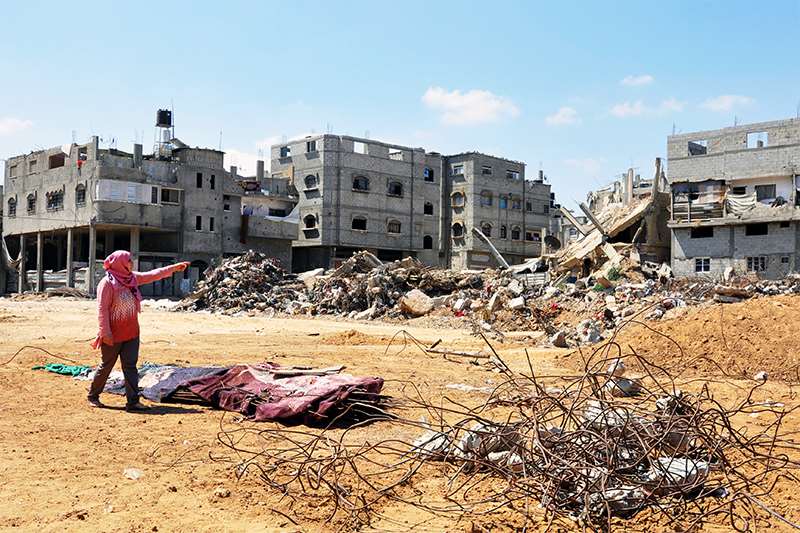 En kvinne peker på det som en gang var en helsestasjon. Gaza, 2015. Foto: Kirsti Næss/Kirkens Nødhjelp