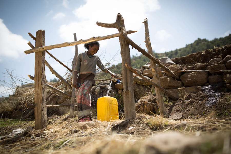 Kvinne som heller vann i en gul kanne i Etiopia