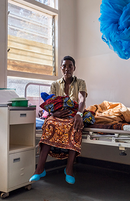 Agnes Lungu foran huset der hun fødte seks barn – og mistet ett. Lille Mana ble født på Lunjika-klinikken. Det reddet livet til dem begge. Foto: Kristin Morseth / Kirkens Nødhjelp.