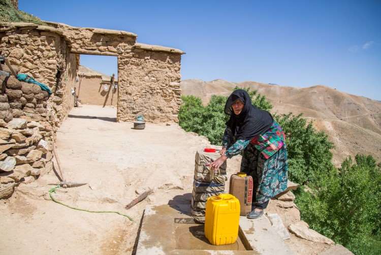 Kvinne som tapper vann i en kanne i Afghanistan
