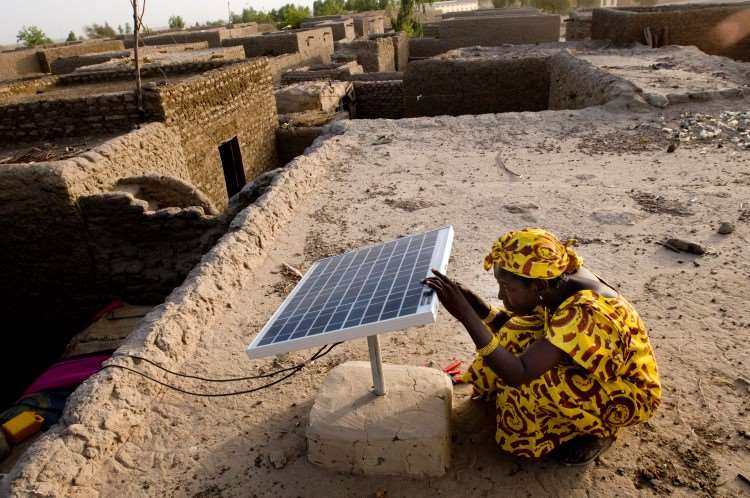 En kvinne som tar på et solcelle-panel i Mali