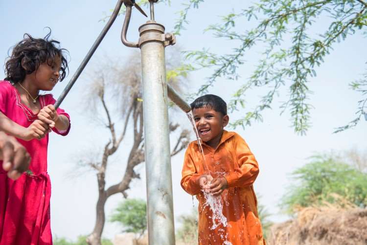 barn som står og får rent vann