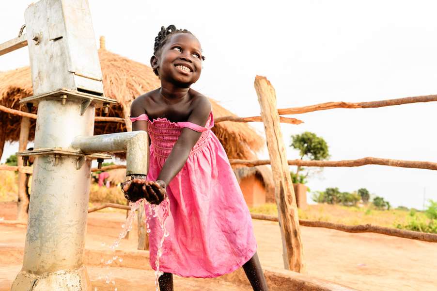 Bilde viser en glad liten jente som smiler og vasker hendene sine