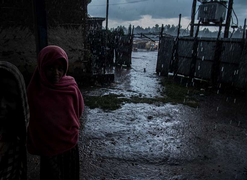 En ung jente som står ute i et dystert regnvær