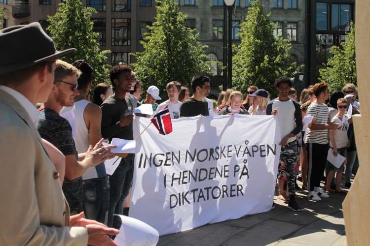 mennesker som holder et stort budskap med følgende tekst: ingen norske våpen i hendene på diktatorer